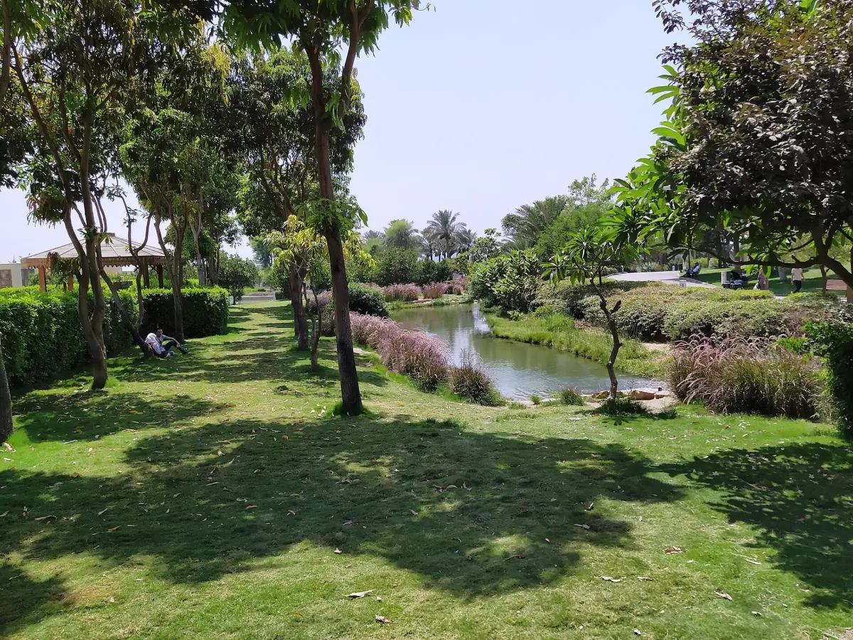 Grüne Rasenflächen, Bäume und ein kleiner Teich im Al-Azhar-Park