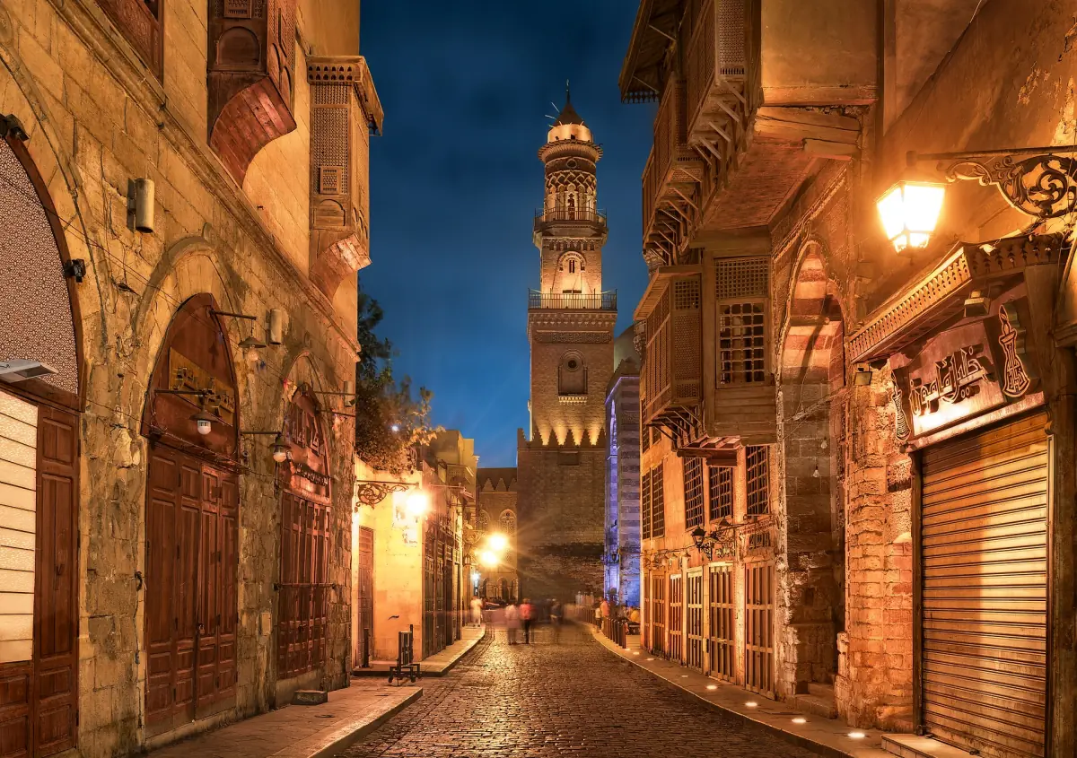Historische Gasse in Kairo mit beleuchtetem Minarett in der Dämmerung