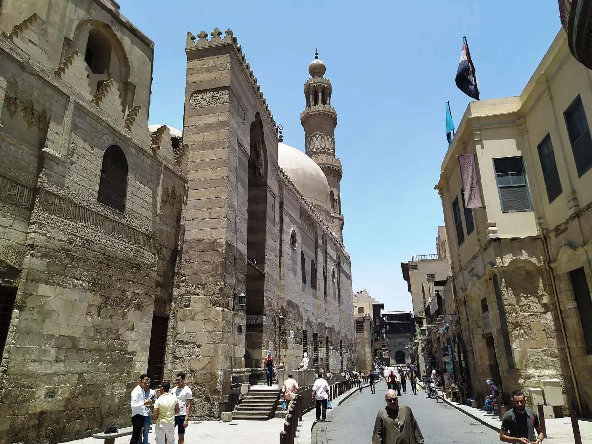 Enge Straße mit einer historischen Madrasa und einem Minarett in Kairo